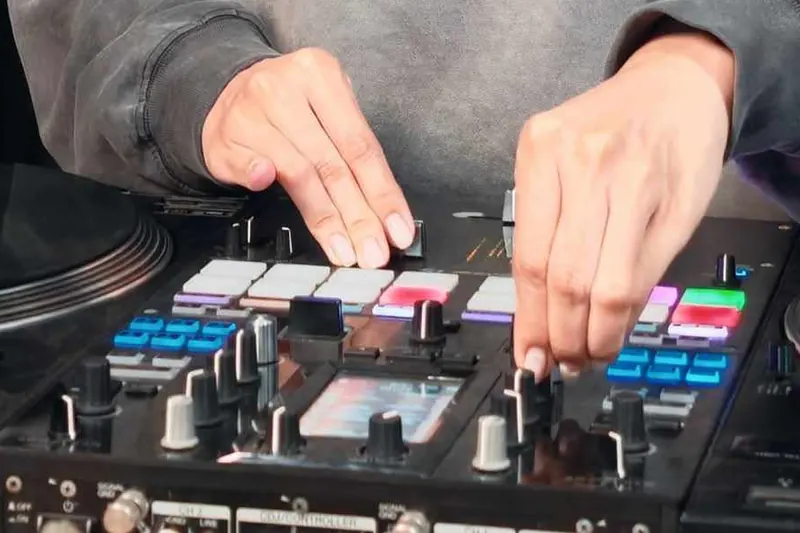 มือกำลังเล่นแพดและปุ่มบนคอนโทรลเลอร์ DJ