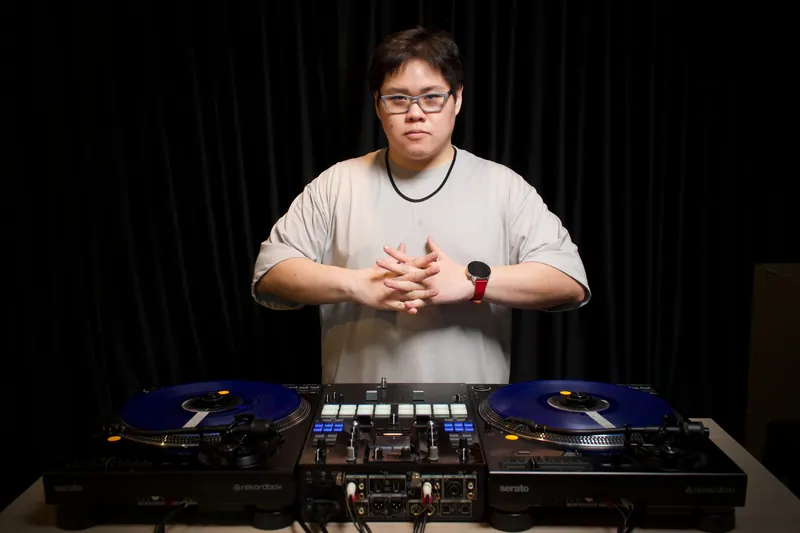 Nutty อาจารย์ DJ LAB SIAM ยืนหลังเทิร์นเทเบิลสองเครื่องและมิกเซอร์