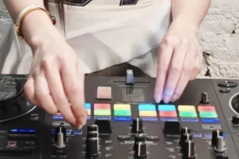 มือกำลังเล่นแพดบนคอนโทรลเลอร์ DJ